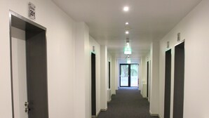 A long, narrow hallway with a carpeted floor, white walls, and doors on both sides. - Hotel Bei Yasemin (Dorsten)