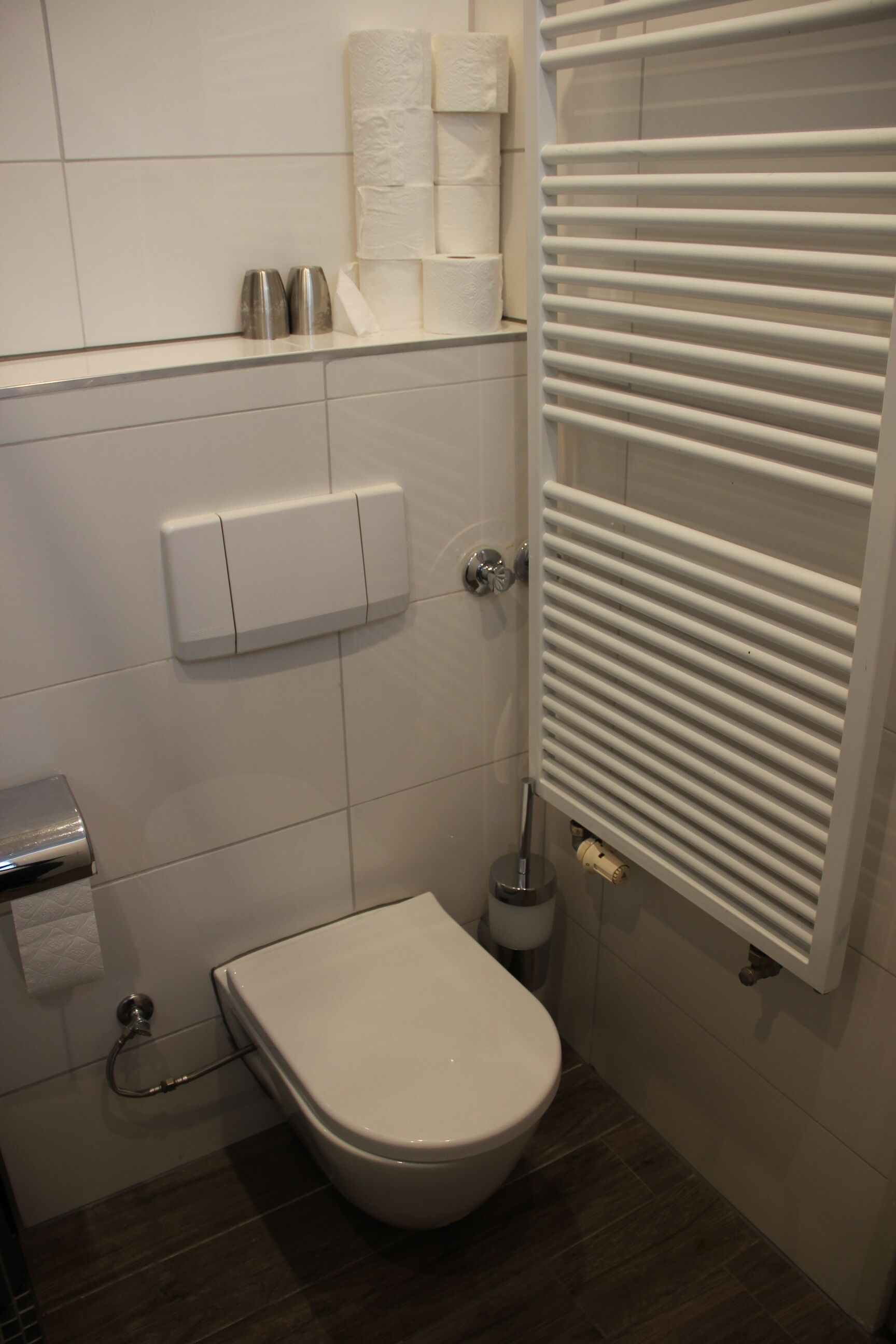 Een badkamer met een toilet, een papieren handdoekdispenser en een handdroger.