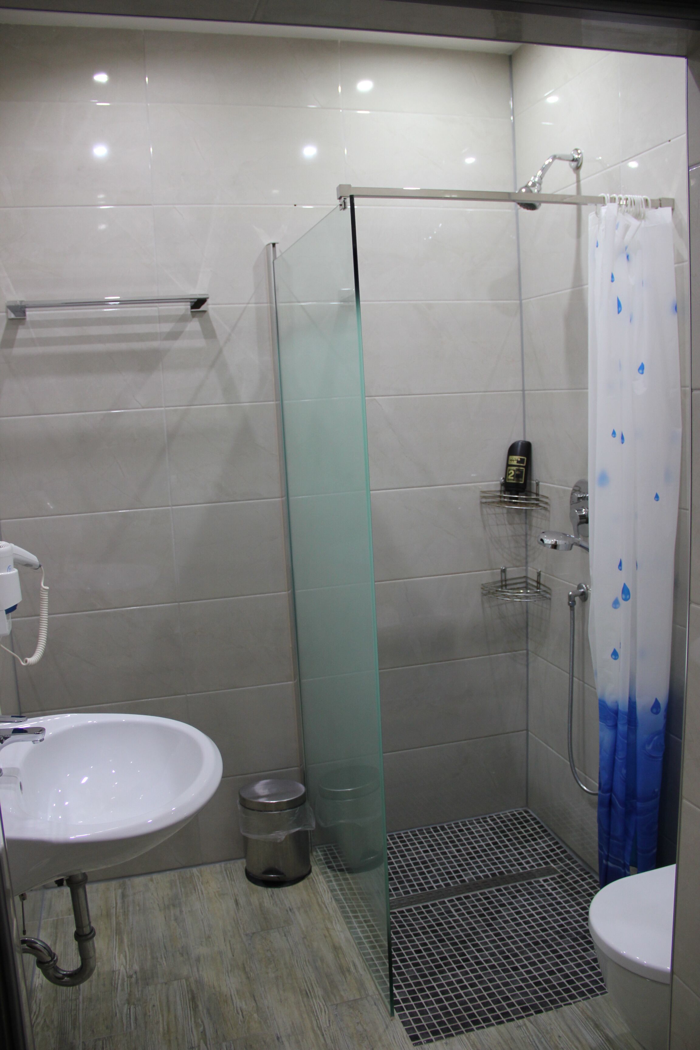 Un baño moderno con ducha envuelta en vidrio, lavamanos blanco y retrete.