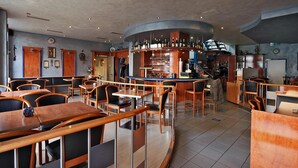 A modern bar area with wooden furniture and a curved counter. - Hotel Bei Yasemin (Dorsten)