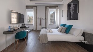 A modern hotel room with a bed, a desk, a chair, and a TV. - Argentina Suites (Rome)