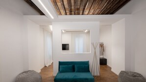 A modern living room with a teal sofa, wooden flooring, and a minimalist design. - Argentina Suites (Rome)