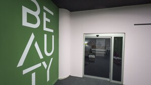 Een groene wand met de tekst 'BEAUTY' en een glazen deur die naar een ruimte leidt.
