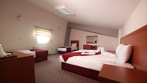 Een hotelkamer met een groot bed, een bureau, een stoel, een dressoir en een raam met zonwering.