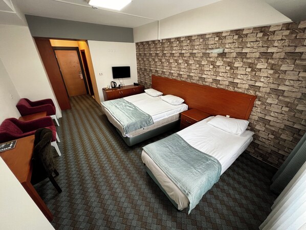 A hotel room with two beds, a TV, a wooden headboard, and a stone-patterned wall. - Erciyes Hill Hotel (Kayseri)