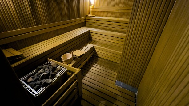 Een sauna met houten banken en een stenen wasbak.