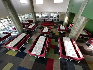 A spacious indoor dining area with multiple tables and chairs, large pillars, and a view through large windows. - Erciyes Hill Hotel (Kayseri)