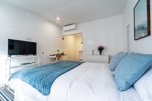 A modern hotel room with a large bed, a TV, a desk, and a small sitting area. - Guadalupe Lofts (Braga)