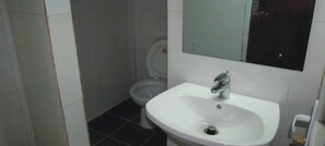 Un baño con un lavamanos blanco, un espejo y un inodoro.