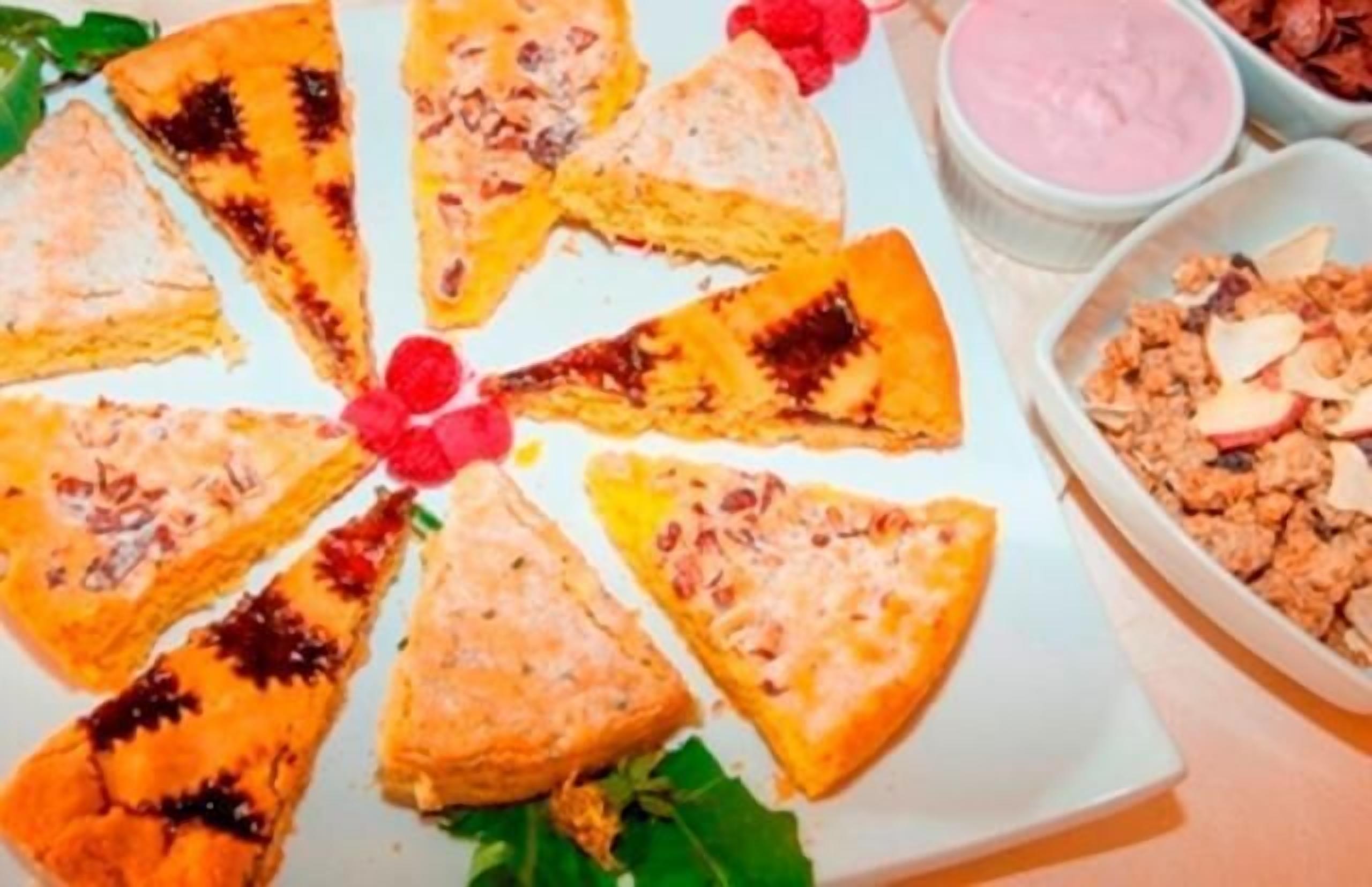 Un piatto di pasticcini triangolari con crosta dorata, guarnito con bacche rosse e foglie verdi.