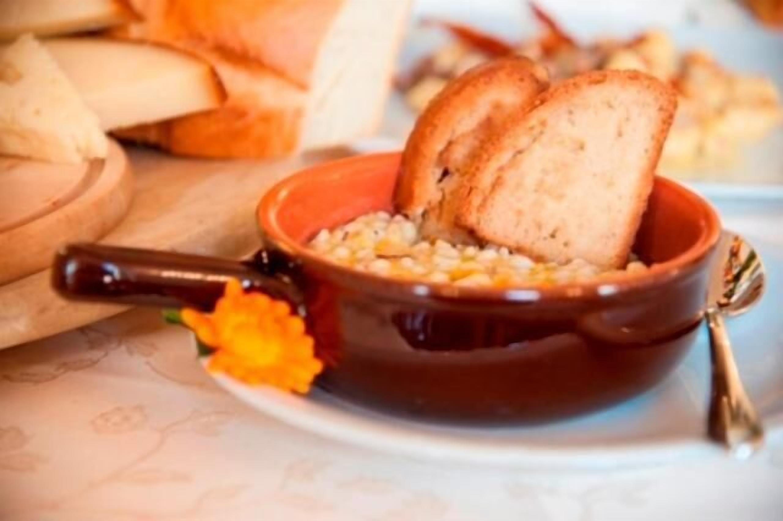 A bowl of soup with bread on the side.
