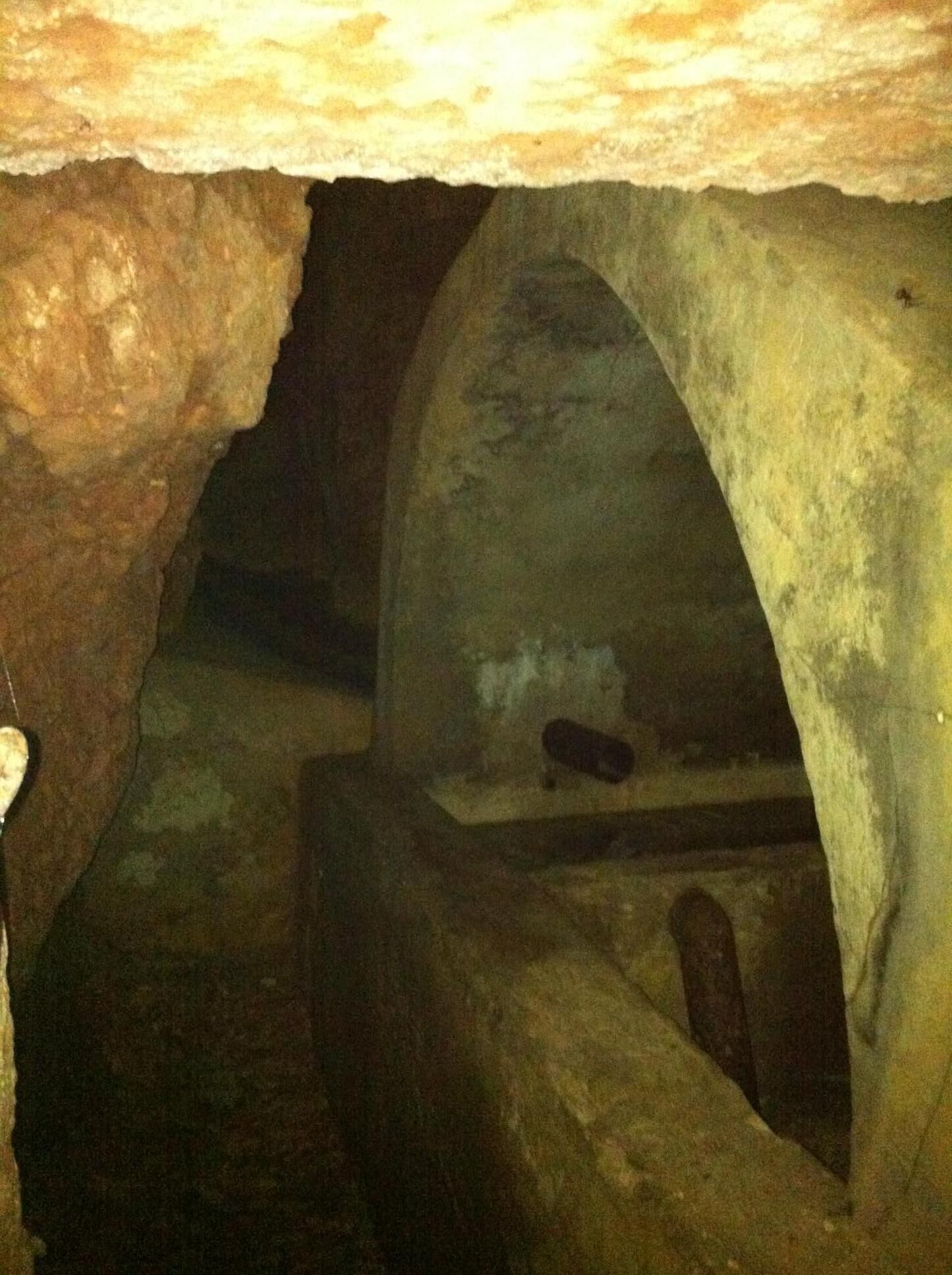 A dimly lit underground passage with rough stone walls and a low ceiling.