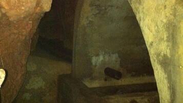 A dimly lit underground passage with rough stone walls and a low ceiling.