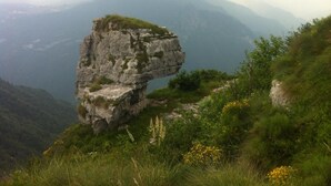 A natural rock formation with a grassy area and wildflowers. - Locanda Alla Stella (Roana)