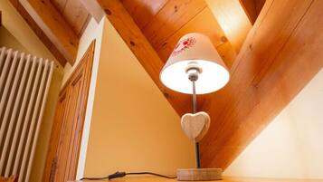 Un plafond en bois à pente douce, un radiateur blanc et une lampe de table dont le pied est en forme de cœur.