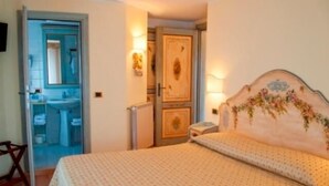 A bedroom with a bed, a nightstand, a mirror, and a door leading to a bathroom. - Locanda Alla Stella (Roana)