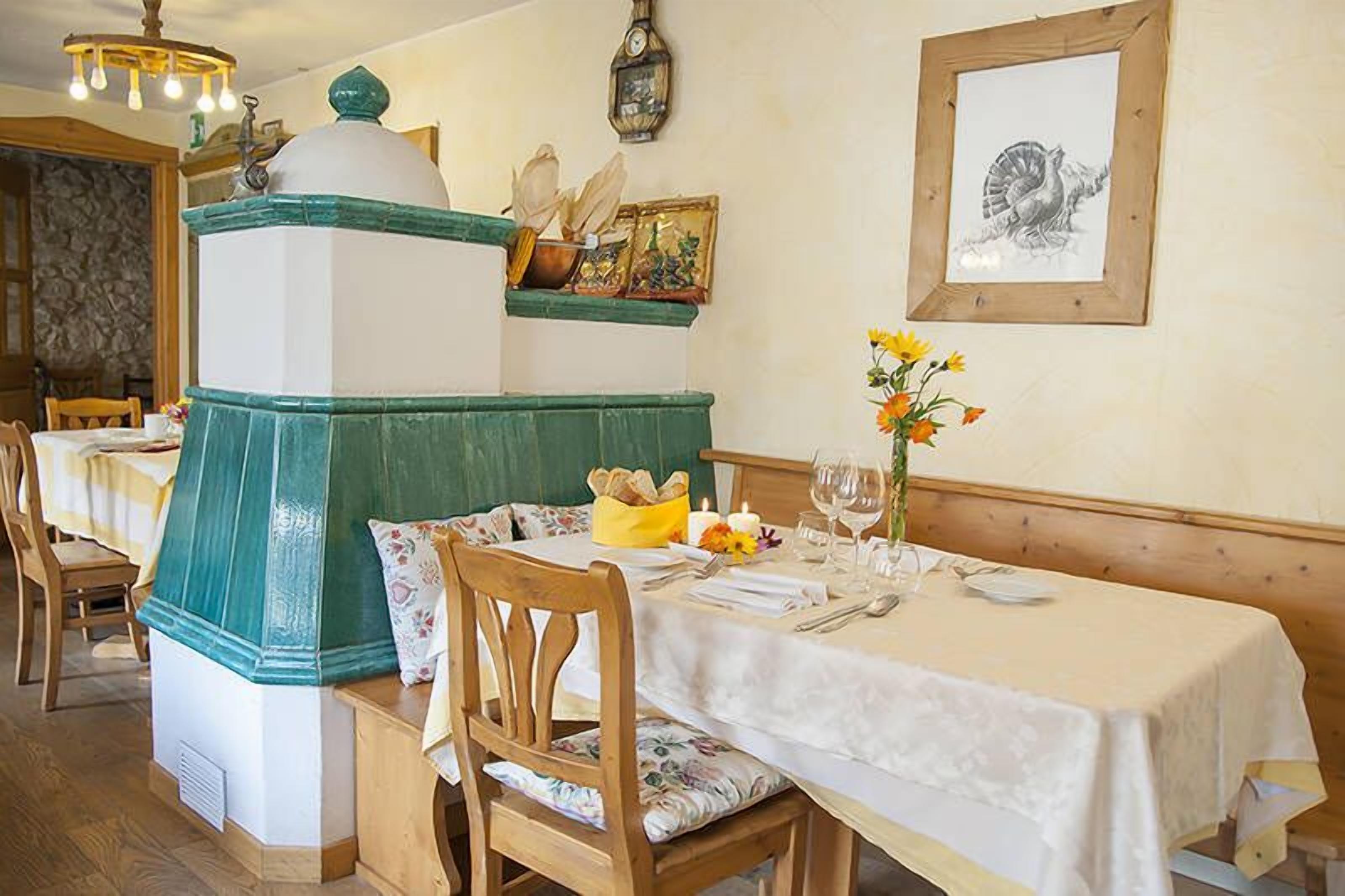 A dining area with a table set for two, a green and white decorative structure, and a framed drawing on the wall.