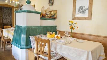 A dining area with a table set for two, a green and white decorative structure, and a framed drawing on the wall.