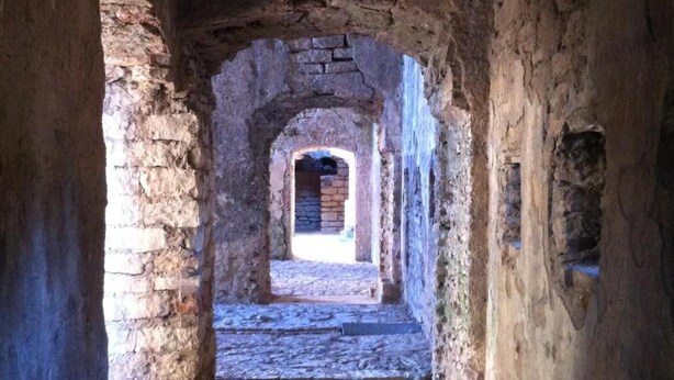 A narrow stone corridor with an arched doorway leading to a brighter area. - Locanda Alla Stella (Roana)
