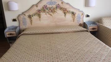 A bed with a floral headboard, two bedside tables, and two wall-mounted lamps.