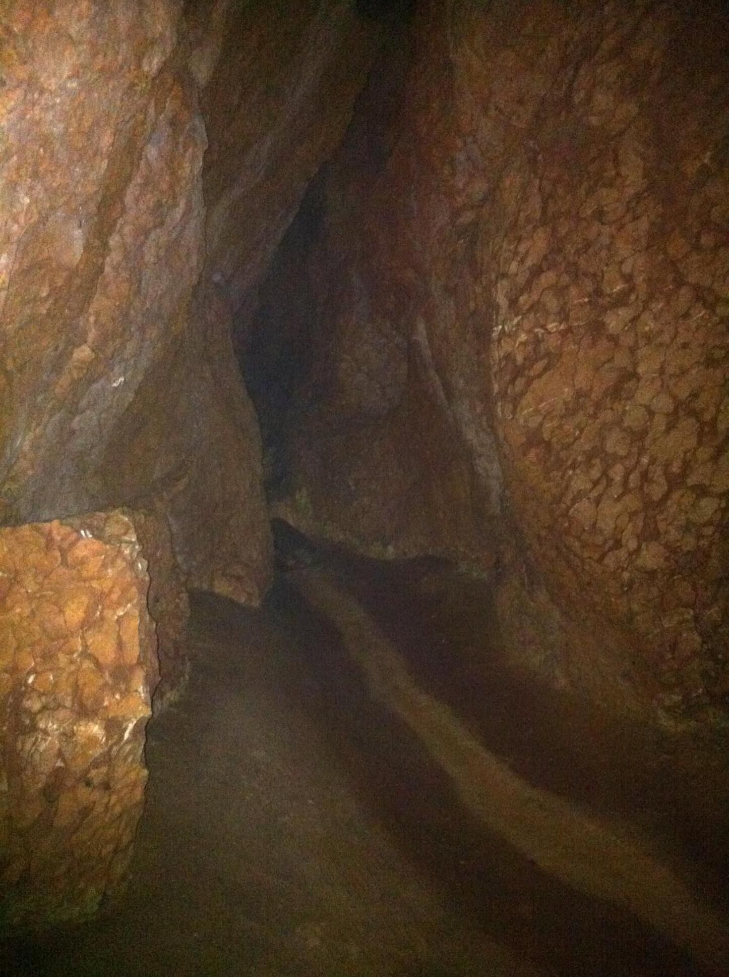 Un estrecho pasaje con paredes rugosas e irregulares y una formación rocosa visible.