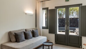 Una habitación moderna con sofá, una mesita redonda y un conjunto de puertas dobles que dan a un espacio exterior.