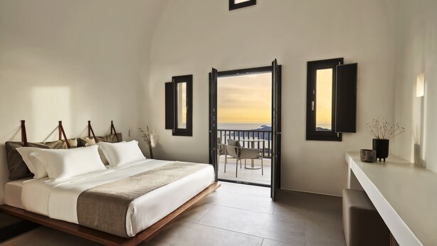 Un dormitorio con cama, balcón y escritorio.