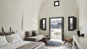 Un dormitorio moderno con cama, sofá, una mesita y vistas al exterior.