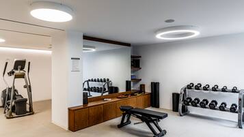 Un gimnasio moderno con equipo de ejercicio, una banca y un soporte para pesas.