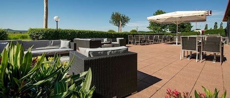 An outdoor patio with wicker furniture, a pergola, and a view of the landscape.