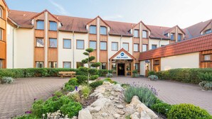 A hotel with a central entrance, multiple windows, and a brick pathway leading to the entrance.