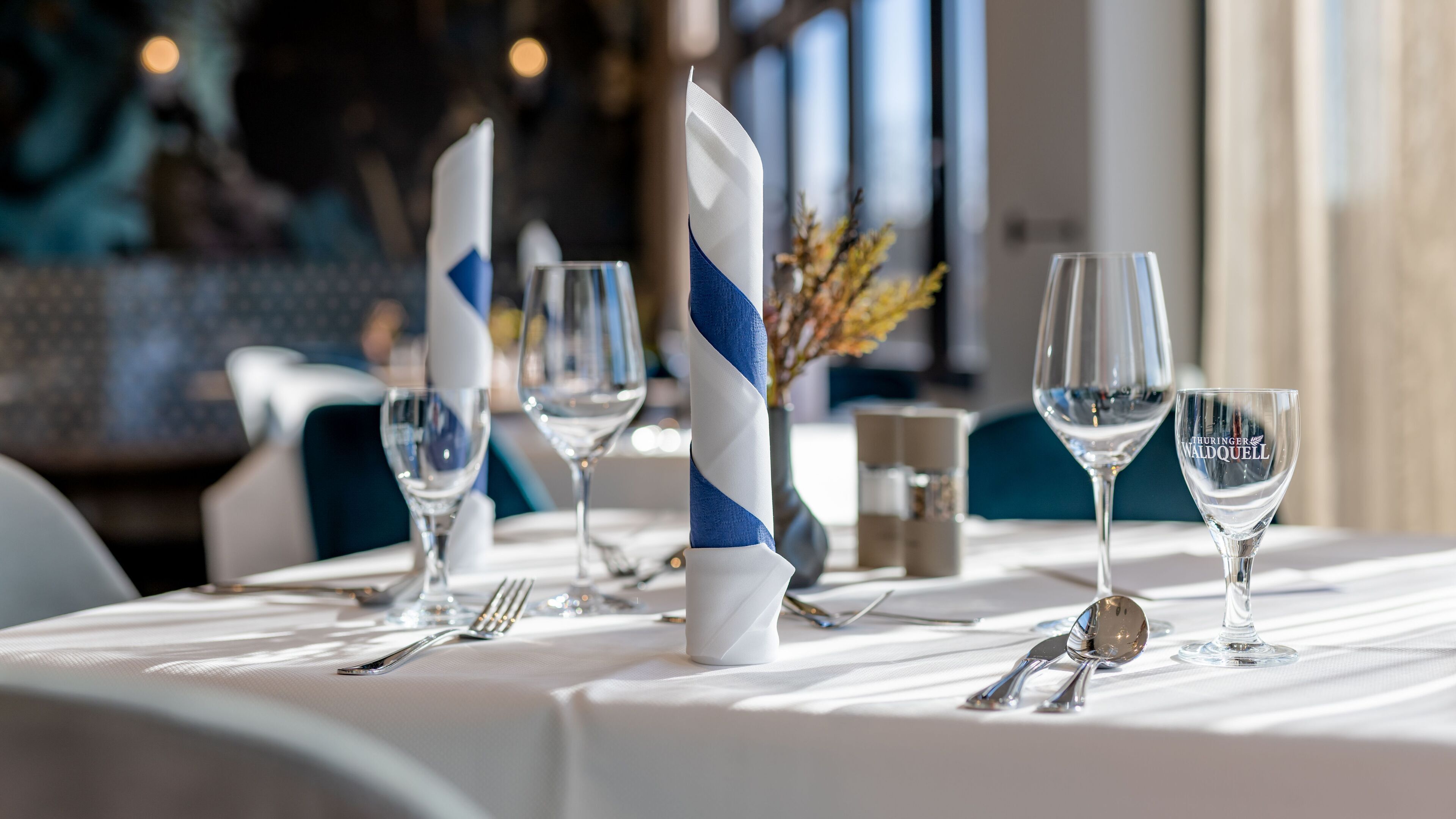 A table set with wine glasses, cutlery, and napkins.