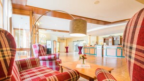A lobby with plaid-patterned seating, a reception desk, and a kitchen area.