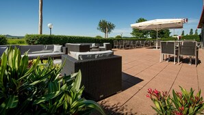 An outdoor patio with wicker furniture, a pergola, and a view of the landscape.