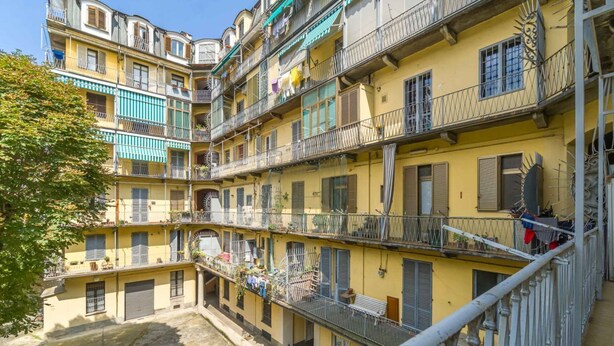 Un edificio de varios pisos con balcones, ventanas y un patio.