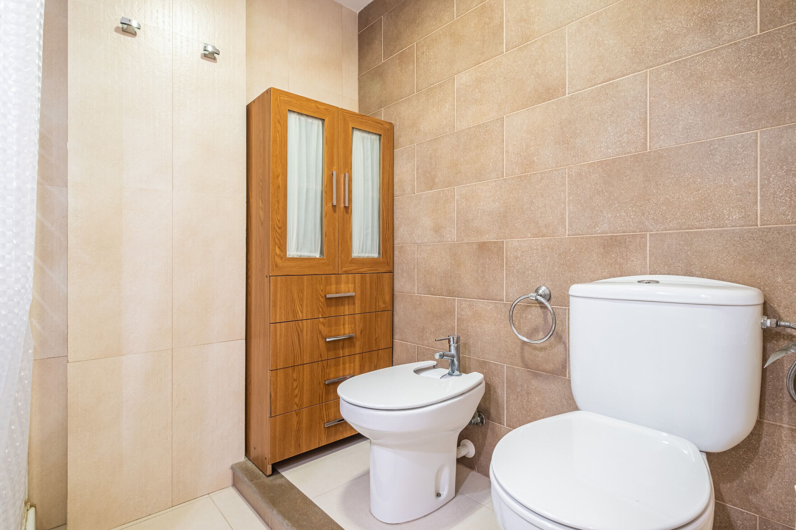 Une salle de bain avec un meuble en bois, un bidet et des toilettes.