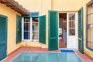 A courtyard with a pool, a door, and a window with shutters. - This 195sqm huge apartment can accommodate up to 7 people. Located on the second and last floor, without a lift, of a historic building dating back to the 13th century in the city center, the apartment is on two levels. Located on the main street of Pisa (Pisa)