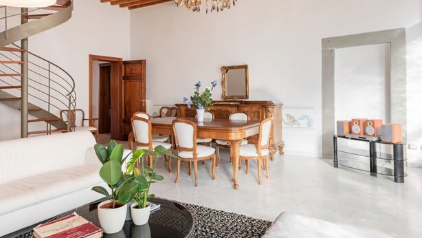 Een moderne woonkamer met een eethoek, een trap en een kroonluchter.