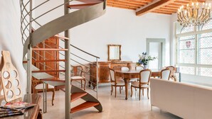Een modern interieur met een wenteltrap, een houten eettafel, stoelen en een kroonluchter.