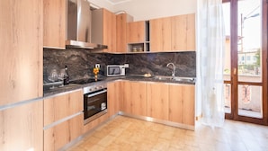 Een moderne keuken met houten kastjes, een marmeren aanrechtblad, een inbouwoven, een magnetron en een spoelbak.