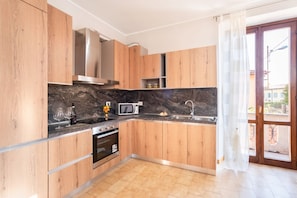Eine moderne Küche mit Holzschränken, einer Marmorarbeitsplatte, einem Backofen, einer Mikrowelle und einem Spülbecken.
