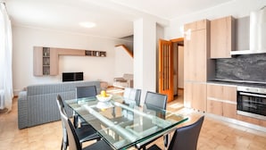 Een moderne keuken met houten kastjes, een glazen eettafel en een inbouwoven.