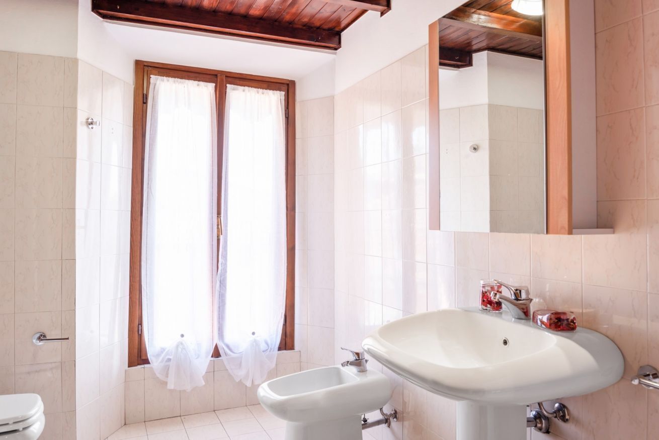 Un bagno con lavandino, bidet e finestra con tende.
