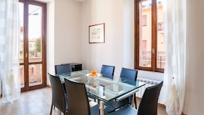 Een eetgedeelte met een glazen tafel, zes stoelen en een schaal fruit.