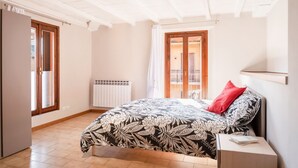 Een slaapkamer met een bed, een radiator, een raam en een deur.