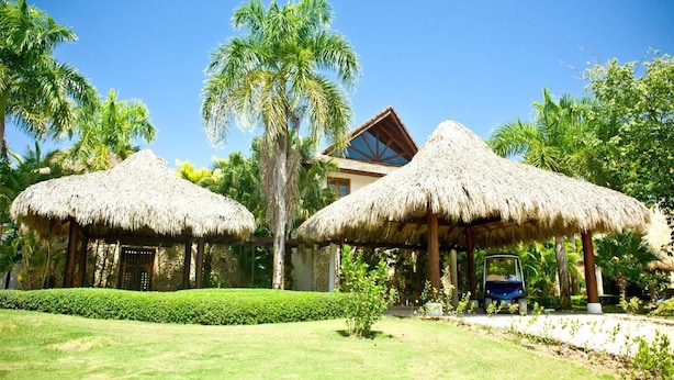 Un resort con strutture a tetto di paglia, palme e cielo azzurro.