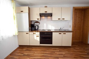 A compact kitchen with wooden cabinets, a built-in oven, a coffee maker, and a sink. - Holiday home Findling Summer - House Findling (Sankt Lambrecht)