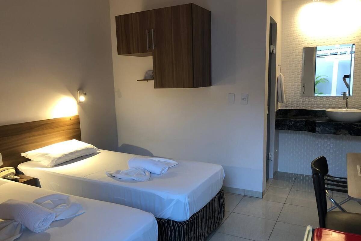 Ett hotellrum med två sängar, ett litet pentry och ett badrum som syns genom en öppen dörr.