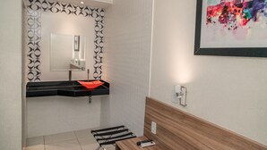 Un baño moderno con un lavabo negro, un espejo y un banco de madera.