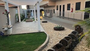 Un patio con un sendero de grava, una vía de tren en miniatura y una zona de estar techada.